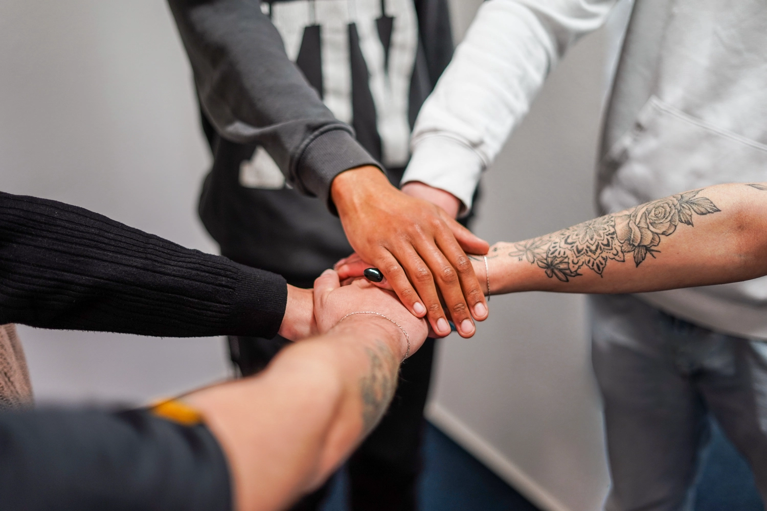 FamilyCare Leipzig UG – Pflegeleistungen für alle Altersgruppen – Eine vielfältige Gruppe von Menschen, die ihre Hände übereinanderlegen und so Teamarbeit, Zusammenhalt und Solidarität symbolisieren.